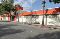 an empty street is seen in front of a building with several palm trees on both sides of the street