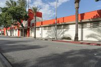 an empty street is seen in front of a building with several palm trees on both sides of the street