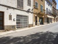 an empty street with old buildings lining it and cars parked on the side of the road