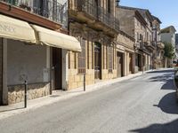 an empty street with old buildings lining it and cars parked on the side of the road