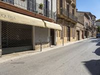 an empty street with old buildings lining it and cars parked on the side of the road