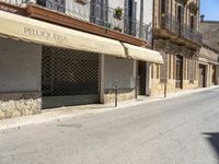 an empty street with old buildings lining it and cars parked on the side of the road