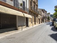 an empty street with old buildings lining it and cars parked on the side of the road