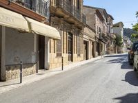 an empty street with old buildings lining it and cars parked on the side of the road