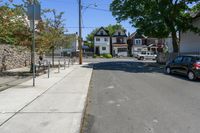 there is a street that looks very quiet with cars parked and trees in front of it