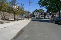 there is a street that looks very quiet with cars parked and trees in front of it