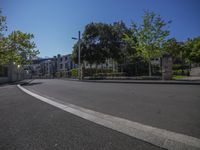 a street with houses and some trees on it near the fenced off area and parking lot