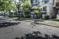 an empty street with buildings in the background and trees on both sides of the street