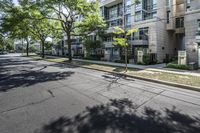 an empty street with buildings in the background and trees on both sides of the street