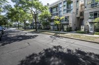 an empty street with buildings in the background and trees on both sides of the street