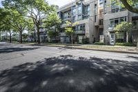 an empty street with buildings in the background and trees on both sides of the street