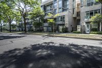 an empty street with buildings in the background and trees on both sides of the street