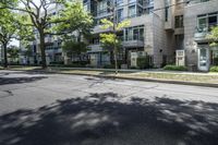 an empty street with buildings in the background and trees on both sides of the street