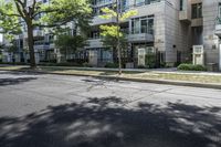 an empty street with buildings in the background and trees on both sides of the street