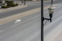 a street light sitting by a white arrow in the middle of a road next to a paved road