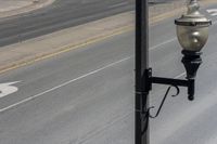 a street light sitting by a white arrow in the middle of a road next to a paved road