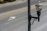 a street light sitting by a white arrow in the middle of a road next to a paved road