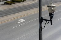 a street light sitting by a white arrow in the middle of a road next to a paved road