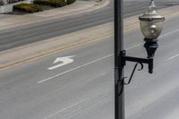 a street light sitting by a white arrow in the middle of a road next to a paved road