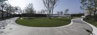 a circular walkway surrounded by green grass and trees with a house in the back ground