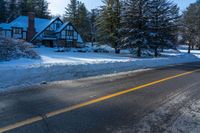 there are snow on the ground and the street is empty outside of the house, with trees lining the front of the house behind it