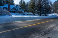 there are snow on the ground and the street is empty outside of the house, with trees lining the front of the house behind it