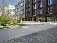 a black building on a street with grass in front of it in the daytime time