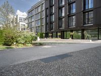 a black building on a street with grass in front of it in the daytime time