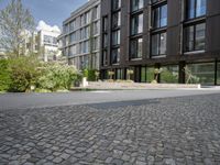 a black building on a street with grass in front of it in the daytime time