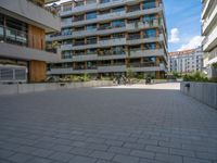 an open courtyard area in front of a residential building with apartments behind it on a clear day