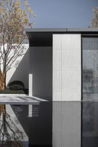 a black and white photograph of a glass door, with trees, buildings, and water