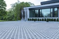 a house with a parking lot that has hedges outside of it, in front of the house