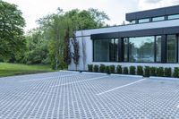 a house with a parking lot that has hedges outside of it, in front of the house