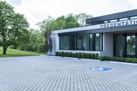 a house with a parking lot that has hedges outside of it, in front of the house