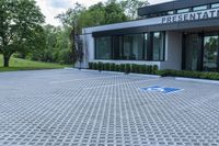 a house with a parking lot that has hedges outside of it, in front of the house