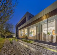 an elegant courtyard with trees, shrubs and gravel flooring are lit up at night