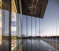 an empty building that looks out into a river area, outside a window and covered in large glass panels