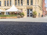 an empty building with two white umbrellas in front of it and some tables outside