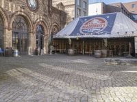 this is a restaurant on the side of a brick street with barrels stacked on top of each other