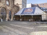 this is a restaurant on the side of a brick street with barrels stacked on top of each other