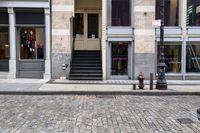 a brick road next to a red fire hydrant near stairs in front of a building
