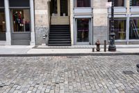 a brick road next to a red fire hydrant near stairs in front of a building