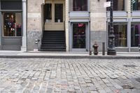 a brick road next to a red fire hydrant near stairs in front of a building
