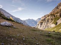 a person riding a horse in a mountainside setting setting in the sun and some rocks