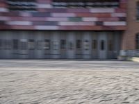a blurry photo of a person riding a bike on an urban street with a building in the background
