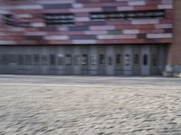 a blurry photo of a person riding a bike on an urban street with a building in the background