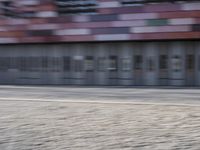 a blurry photo of a person riding a bike on an urban street with a building in the background