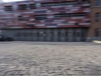 a blurry photo of a person riding a bike on an urban street with a building in the background