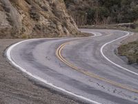 a man riding on the back of a white motorcycle down a curvy road