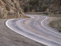 a man riding on the back of a white motorcycle down a curvy road